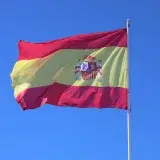 Vibrant Spanish flag waving against a clear blue sky in Cádiz, Andalucía, España.