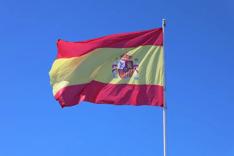Vibrant Spanish flag waving against a clear blue sky in Cádiz, Andalucía, España.