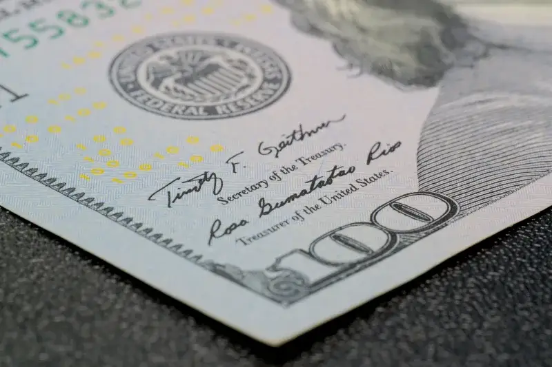 Primer plano de alta resolución de un billete de cien dólares que muestra características de seguridad intrincadas.