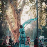 Father and son in Argentina soccer jerseys celebrate outdoors with a flag.