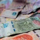 A detailed view of Argentine peso banknotes scattered on a table, showcasing various denominations.