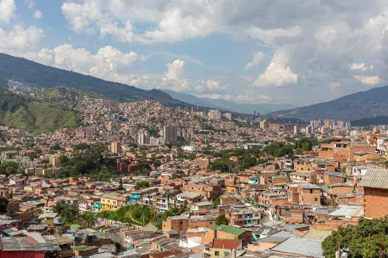 Aerial view of Medellín, Colombia's urban landscape with rolling hills and dense buildings.