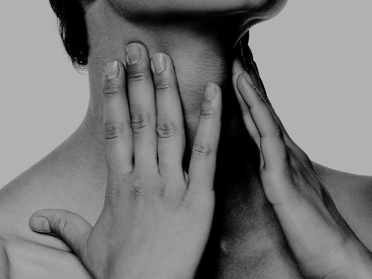 A close up of a person feeling their neck with both hands