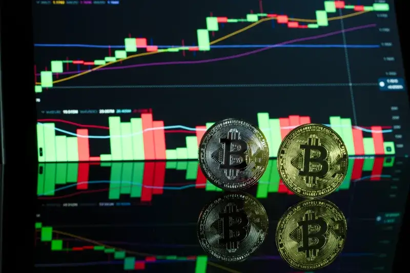 Monedas de Bitcoin frente a un gráfico de trading de criptomonedas que muestra las tendencias del mercado.