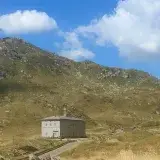A remote building on San Bernardino Pass amidst mountainous terrain under a clear blue sky.
