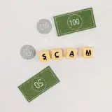 Flat lay of fake currency and scam letters on a gray surface representing financial deception.