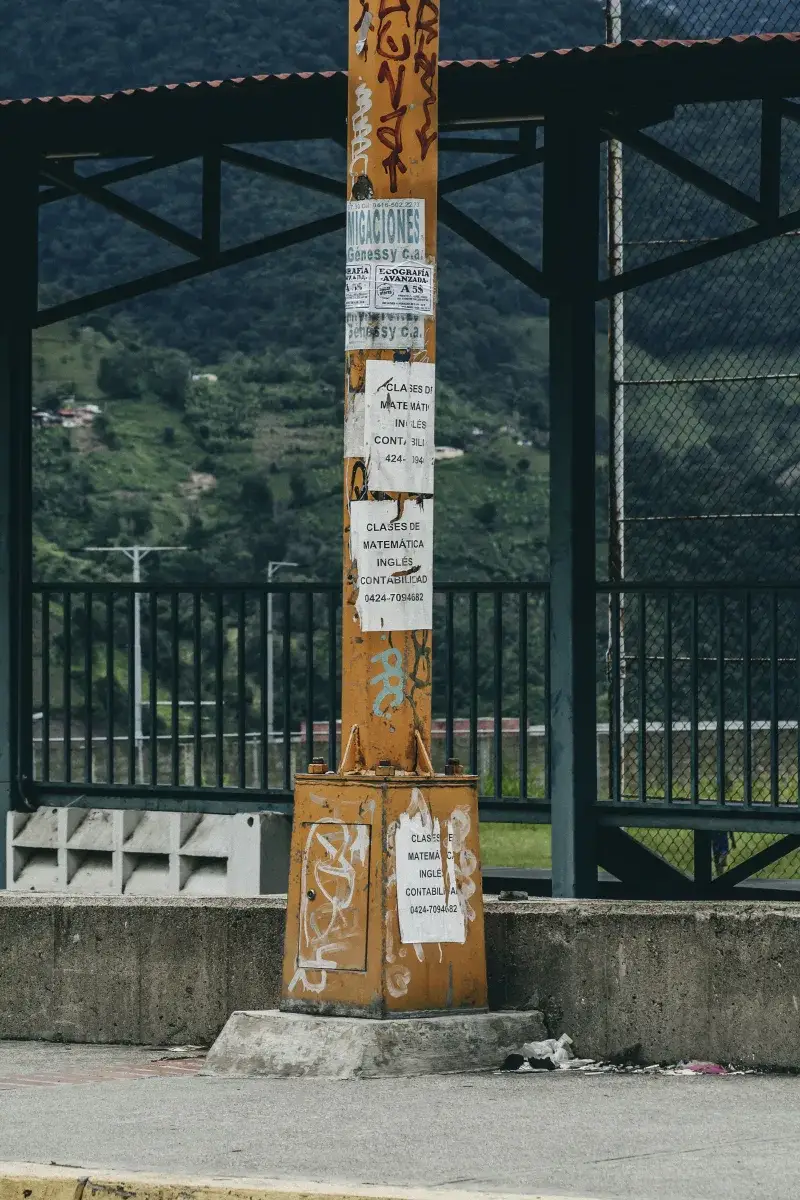 Graffiti-covered orange pole with posters in a townscape of Mérida, Venezuela.
