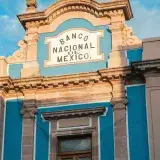 Close-up of the beautiful Banco Nacional de Mexico facade with blue accents against a cloudy sky.