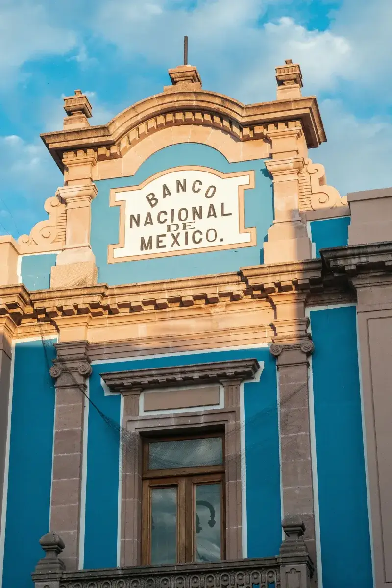 Close-up of the beautiful Banco Nacional de Mexico facade with blue accents against a cloudy sky.