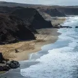 Stunning aerial view of Playa del Viejo Reyes with cliffs and crashing waves in Canary Islands.