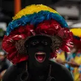A colorful carnival participant in vibrant attire and body paint in Bogotá, Colombia.
