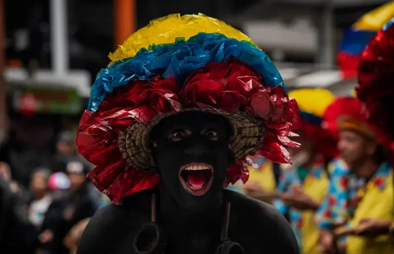 A colorful carnival participant in vibrant attire and body paint in Bogotá, Colombia.