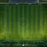 Top-down view of a soccer field with players during daytime.