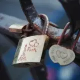 Rusty love padlocks on a Paris bridge, symbolizing romance.