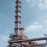 Oil refinery tower against a blue sky in Trzebinia, Poland, showcasing industrial architecture.