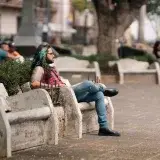 Man with green hair relaxing on a bench in San José, Costa Rica.