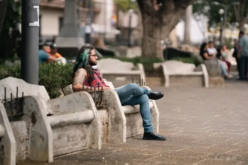 Man with green hair relaxing on a bench in San José, Costa Rica.