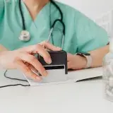 Close-up of a doctor stamping a prescription with a bottle of pills on a desk.