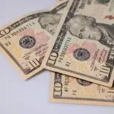 Detailed view of American ten dollar bills scattered on a light surface, showcasing currency features.