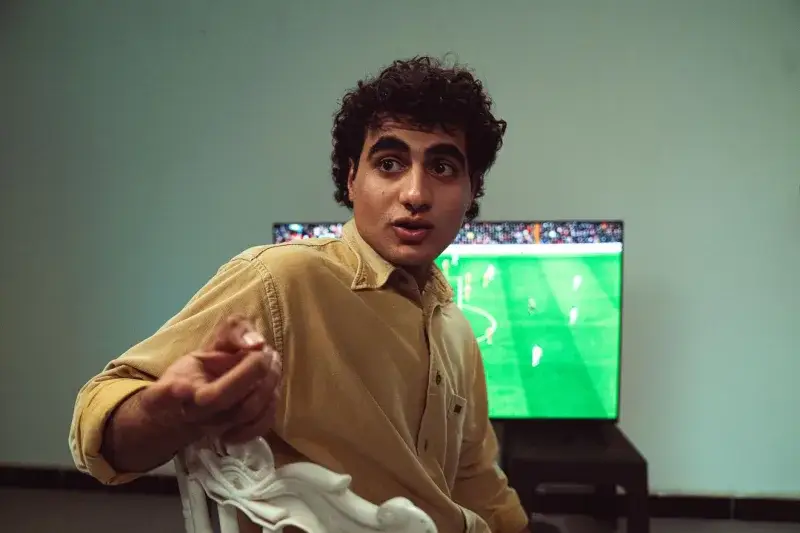 A man engaged in watching a soccer game on TV, expressing emotions.