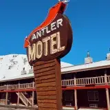 Iconic Antler Motel sign against snowy mountain backdrop in Jackson, Wyoming.