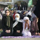 Mujeres musulmanas con hiyab se reúnen al aire libre para orar en Gaza, resaltando tradiciones culturales y religiosas.