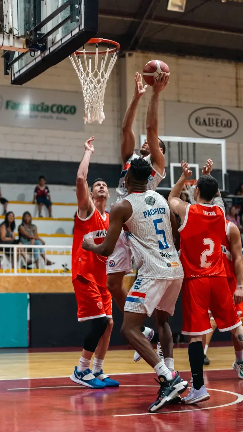 Exciting moment during a competitive basketball game, showcasing players striving for the ball near the basket.