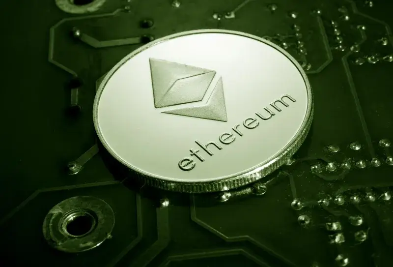 Close-up of an Ethereum coin placed on a circuit board, symbolizing digital currency technology.