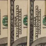 Detailed close-up of multiple US hundred dollar bills, showcasing currency design.