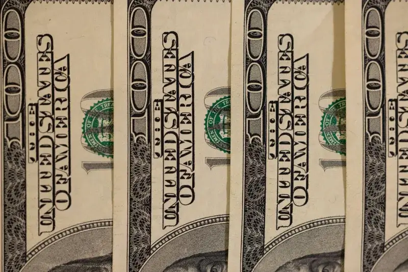 Detailed close-up of multiple US hundred dollar bills, showcasing currency design.