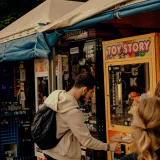 Young man enjoying an outdoor arcade, playing a Toy Story claw machine.