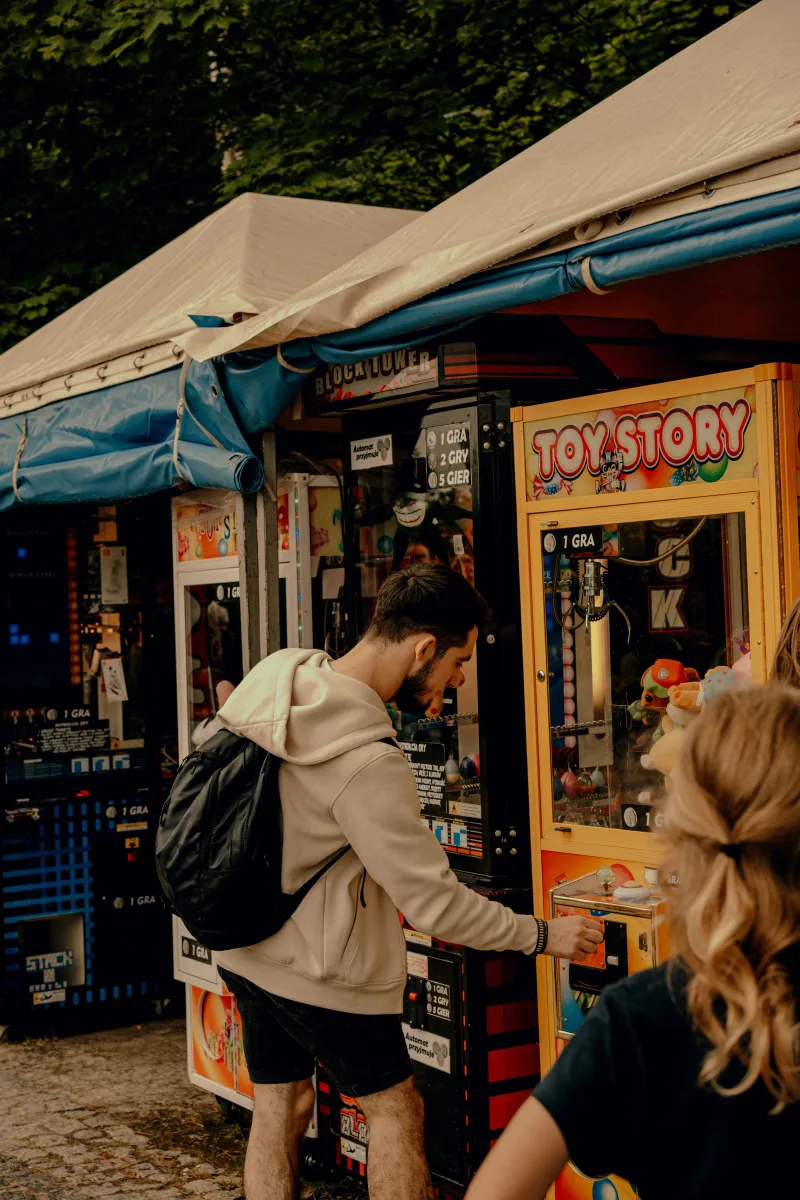 Young man enjoying an outdoor arcade, playing a Toy Story claw machine.
