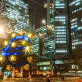 Night view of the iconic Euro sculpture in Frankfurt's bustling financial district.