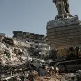 Powerful excavator clearing earthquake debris amidst building ruins in Antakya, Turkey.
