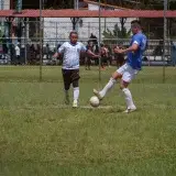 Two male soccer players competing in an outdoor match on a sunny day.
