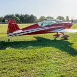 A striking red aerobatic plane on a sunny day at General Rodríguez Airfield, Argentina.