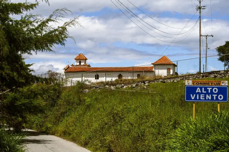 Traditional white building with red tile roof surrounded by greenery in Mérida, Venezuela.