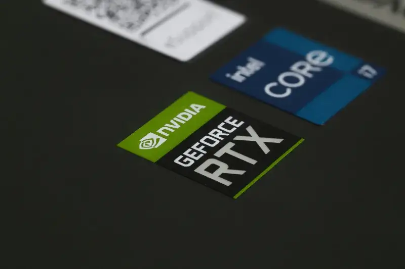 Primer plano de los stickers NVIDIA GeForce RTX e Intel Core i7 en la superficie de una laptop, mostrando tecnología moderna.