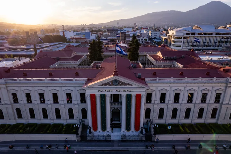 A captivating aerial shot of Palacio Nacional in San Salvador during sunset, showcasing vibrant city life and architecture.