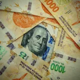 A detailed close-up of Argentinian pesos and a US dollar, showcasing currency contrast.