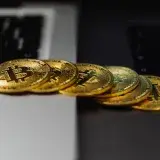 A stack of gold bitcoin coins placed on a laptop keyboard, symbolizing digital currency and finance.