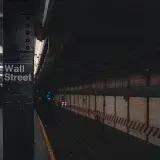 Moody view of Wall Street subway station in New York City, showcasing urban architecture.