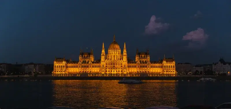 Night view of the glowing Hungarian Parliament Building reflected in the Danube River.
