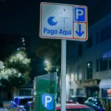 Parking sign with 'Pago Aquí' text in Mexico City at night, featuring parked cars.