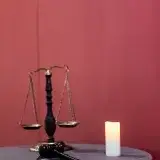 A symbolic display of justice featuring a gavel, scales, and candle on a table.