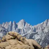 Capture the majestic Mount Whitney with its rugged peaks against a clear blue sky, showcasing natural beauty.