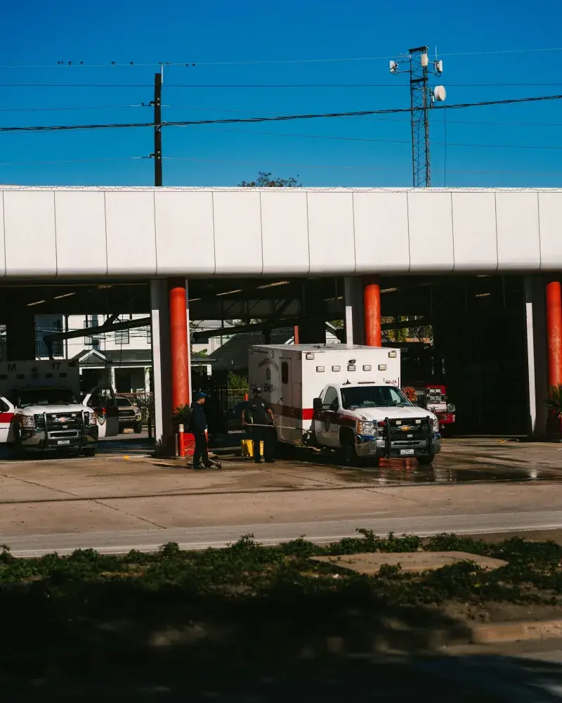 Emergency vehicles parked at a Houston fire station on a sunny day.