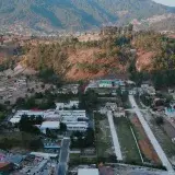 Scenic aerial view of a small town nestled in the mountains with lush forests and winding roads.