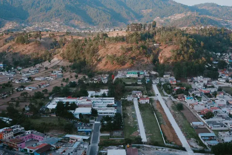 Scenic aerial view of a small town nestled in the mountains with lush forests and winding roads.