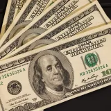 Close-up of US hundred dollar bills fanned out on a black surface for financial themes